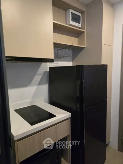 Modern compact kitchen with sleek black appliances and minimalist design