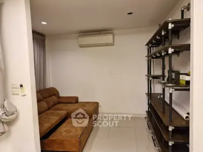 Cozy living room with brown sectional sofa and industrial-style shelving, perfect for modern urban living.