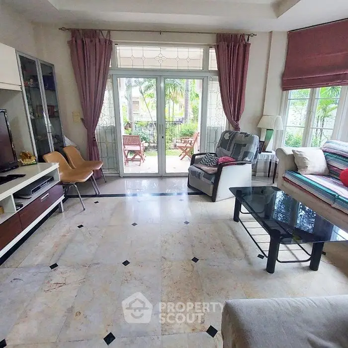 Spacious living room with elegant decor and garden view, featuring large windows and stylish furniture.