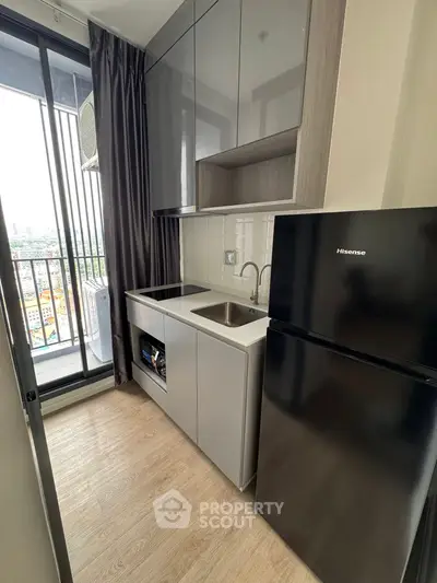 Modern compact kitchen with sleek cabinetry and balcony view
