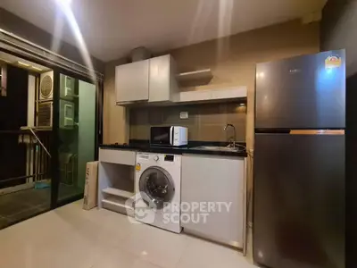 Modern kitchen with appliances including fridge, washing machine, and microwave in sleek design.
