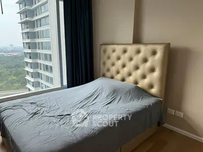 Modern bedroom with large window offering a stunning city view in a high-rise apartment.