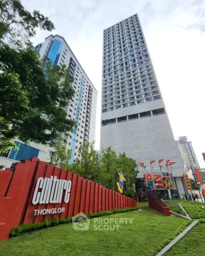 Modern high-rise building with lush green landscaping and vibrant signage in Thonglor area.