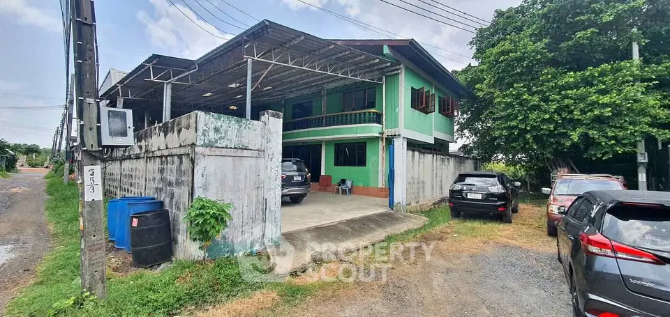 Spacious two-story house with ample parking and lush greenery in a serene neighborhood.