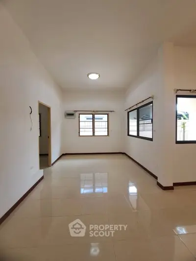 Spacious empty living room with large windows and tiled flooring