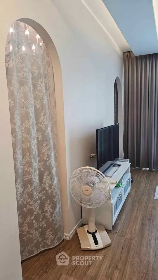 Modern living room with elegant decor and wooden flooring, featuring a TV stand and stylish curtains.