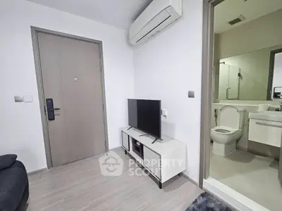 Modern apartment interior with sleek design, featuring a compact living area and adjacent bathroom.