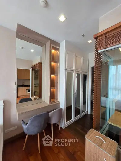 Modern apartment interior with stylish furniture and wooden flooring, featuring a cozy dining area and mirrored storage.