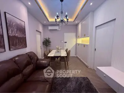 Modern living room with elegant chandelier, leather sofa, and dining area in a stylish apartment.