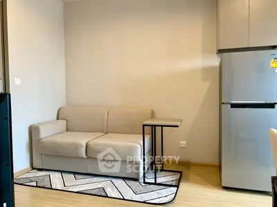 Cozy modern living area with compact sofa and sleek refrigerator