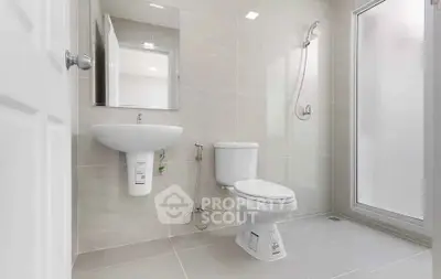 Modern bathroom with sleek fixtures and neutral tiles, featuring a shower and toilet.