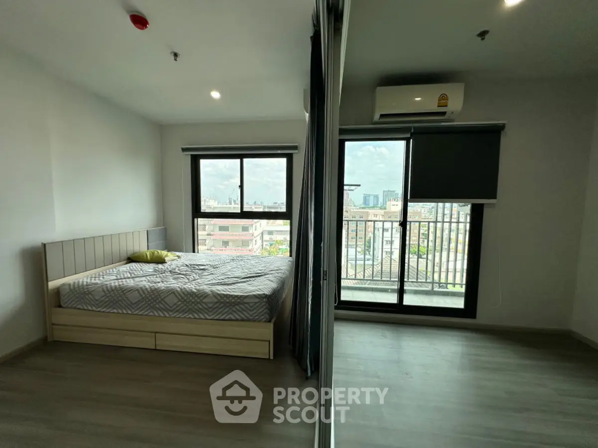 Modern bedroom with large window and city view, featuring sleek design and ample natural light.