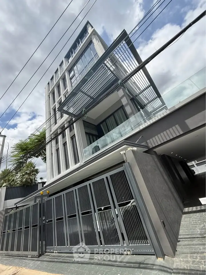 Modern multi-story building with sleek design and glass facade under a cloudy sky.
