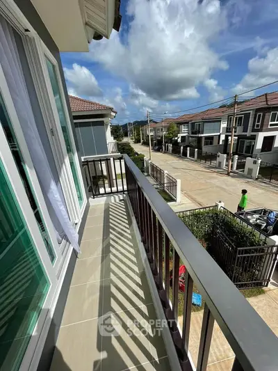 Charming balcony view in a modern residential neighborhood with clear skies and stylish architecture.