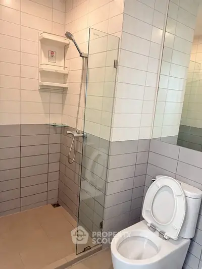 Modern bathroom with glass shower and tiled walls in a contemporary home.