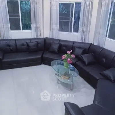 Spacious living room with modern black leather sectional sofa and glass coffee table, perfect for relaxation.
