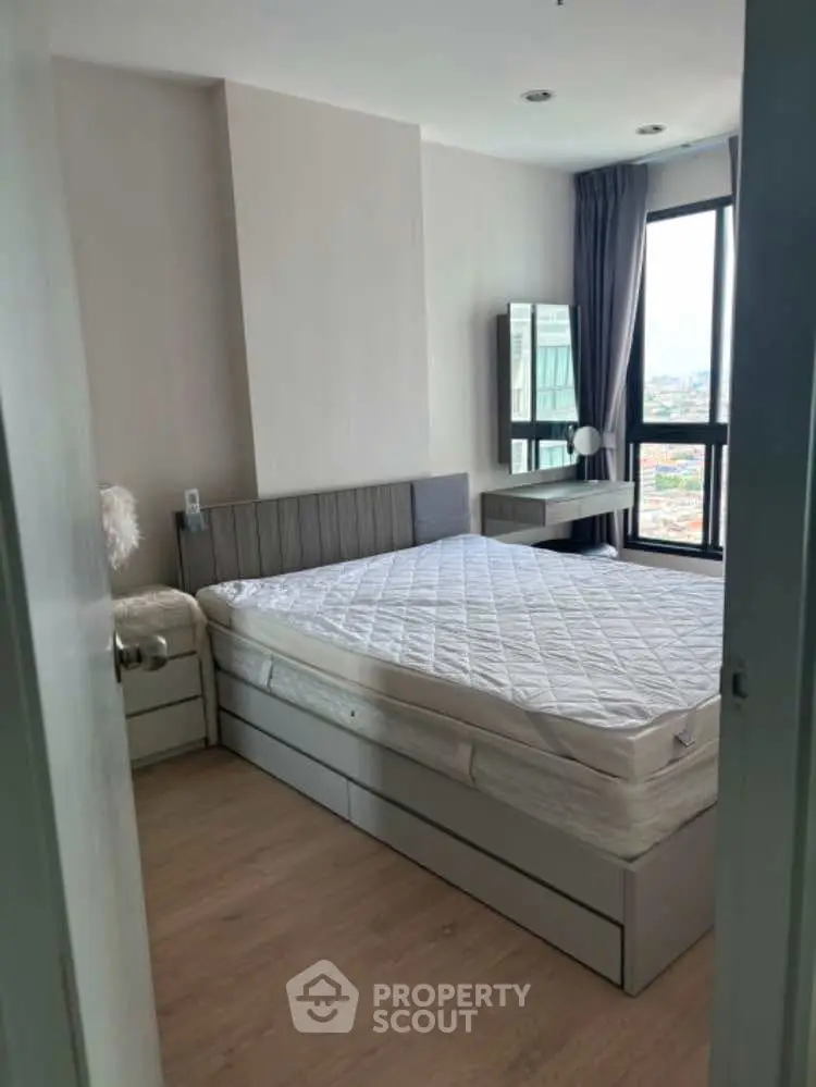 Modern bedroom with large window and city view, featuring sleek furniture and neutral tones.