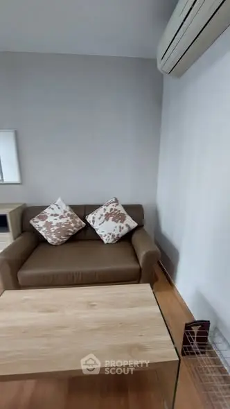 Cozy living room with brown sofa, stylish cushions, and air conditioning for comfort.