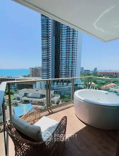 Luxurious balcony with stunning ocean view and outdoor bathtub in high-rise apartment.