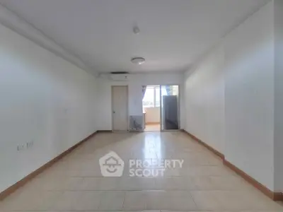 Spacious empty living room with tiled flooring and balcony access, perfect for customization.