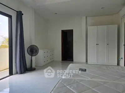 Spacious bedroom with balcony access, featuring modern furniture and ample natural light.