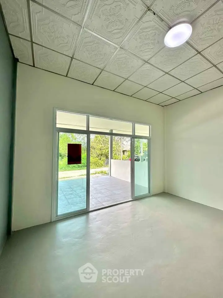 Spacious room with large windows opening to a serene garden view, ideal for natural light lovers.