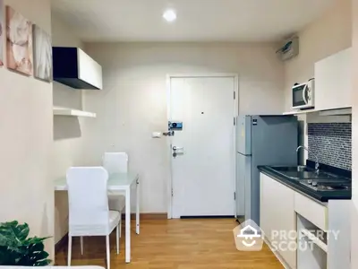 Cozy kitchen with modern appliances and a compact dining area, featuring a clean design with ample lighting and wooden flooring.