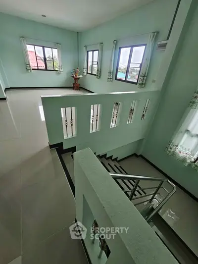 Spacious two-story home with large windows and modern staircase, offering abundant natural light and open living space.