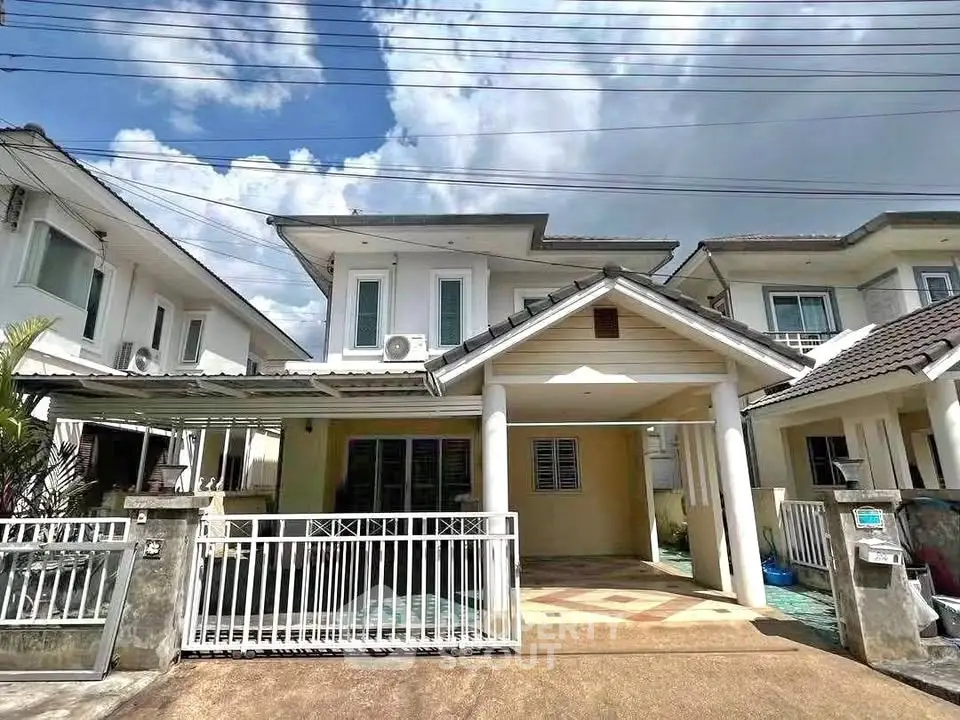 Charming two-story house with gated entrance and spacious driveway under a clear blue sky.