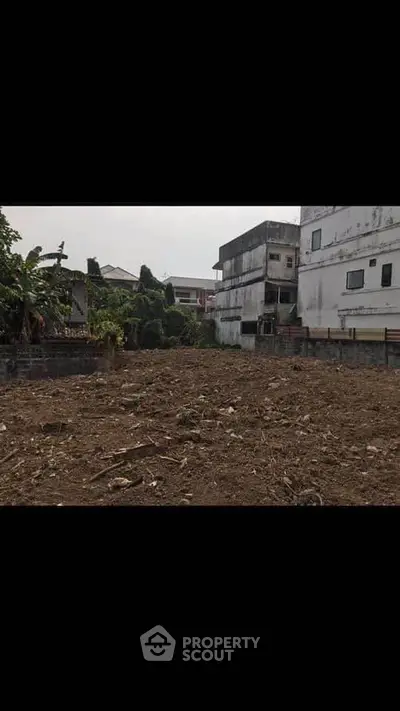 Vacant land plot in urban area ready for development, surrounded by residential buildings.