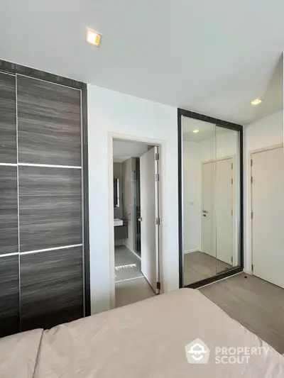 Modern bedroom with mirrored closet and en-suite bathroom in stylish apartment