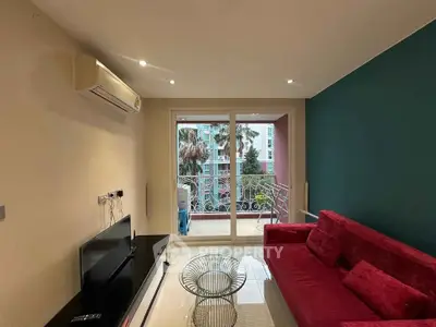 Modern living room with vibrant red sofa and balcony view in stylish apartment.