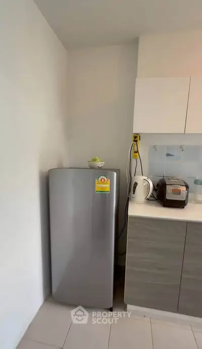 Modern kitchen corner with sleek fridge and appliances, perfect for compact living spaces.