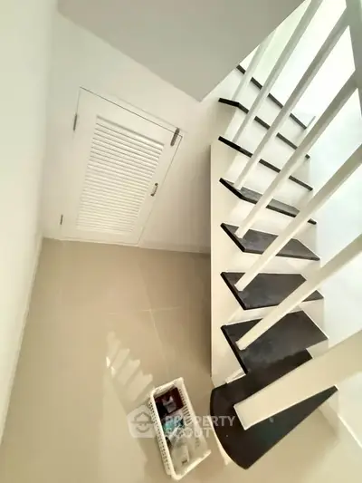 Modern staircase with sleek black steps and storage area underneath