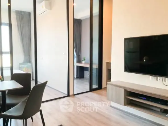 Modern living room with sleek furniture and large TV, open layout design.