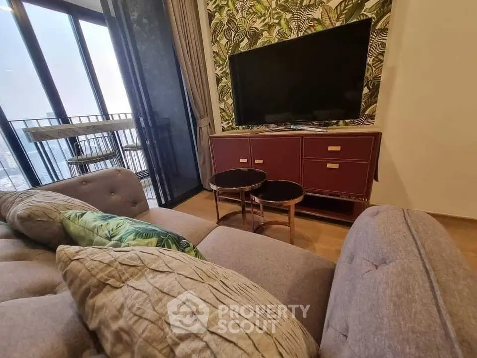 Stylish living room with modern decor and balcony view, featuring a cozy sofa and large TV.