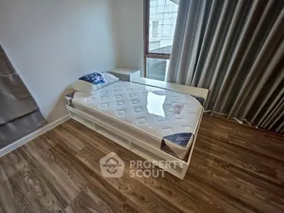 Modern bedroom with single bed and wooden flooring, featuring large window and elegant curtains.
