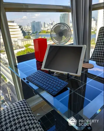 Modern study area with glass desk and city view, featuring tablet and keyboard setup.