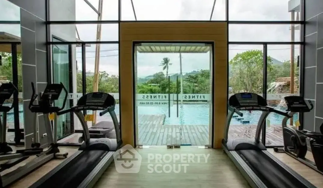 Luxurious gym with pool view and modern fitness equipment in a serene setting.