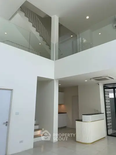 Modern two-story interior with sleek staircase and open layout, featuring minimalist design and ample natural light.