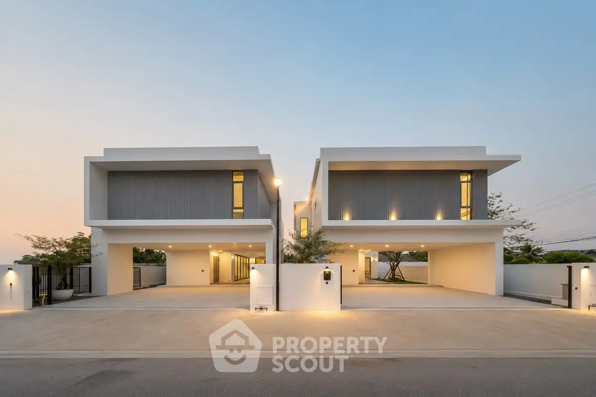 Modern luxury duplex with sleek design and spacious driveway at sunset.
