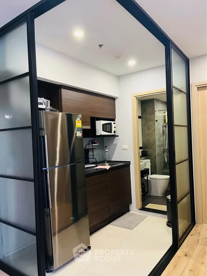 Modern compact kitchen with sleek appliances and sliding glass doors in a stylish apartment.
