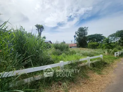 Scenic rural landscape with lush greenery and white fence under a blue sky, perfect for countryside living.
