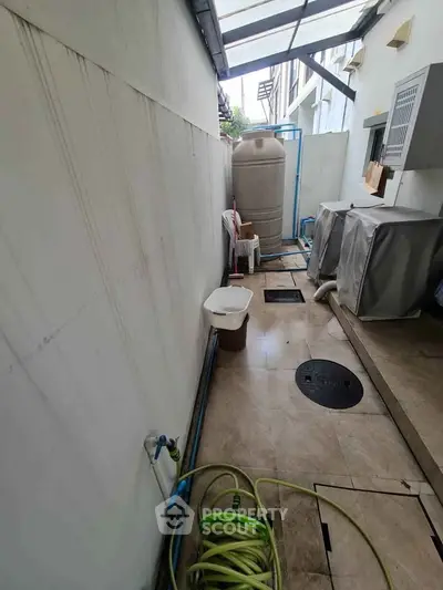Outdoor utility area with water tank and hose in residential property