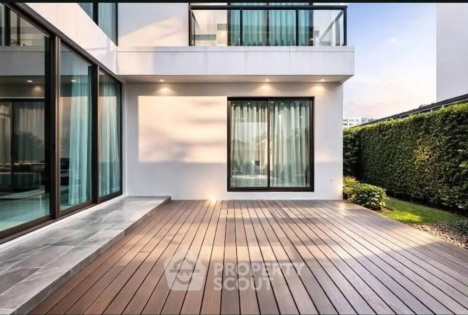 Modern luxury home with spacious wooden deck and large glass windows, perfect for outdoor relaxation.