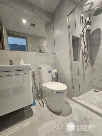 Modern bathroom with sleek marble tiles, glass shower, and contemporary fixtures, perfect for a luxurious urban living experience.