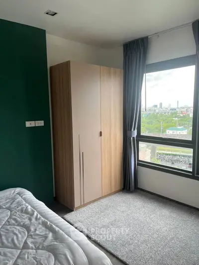 Bright bedroom with large window offering stunning city view and modern wardrobe.