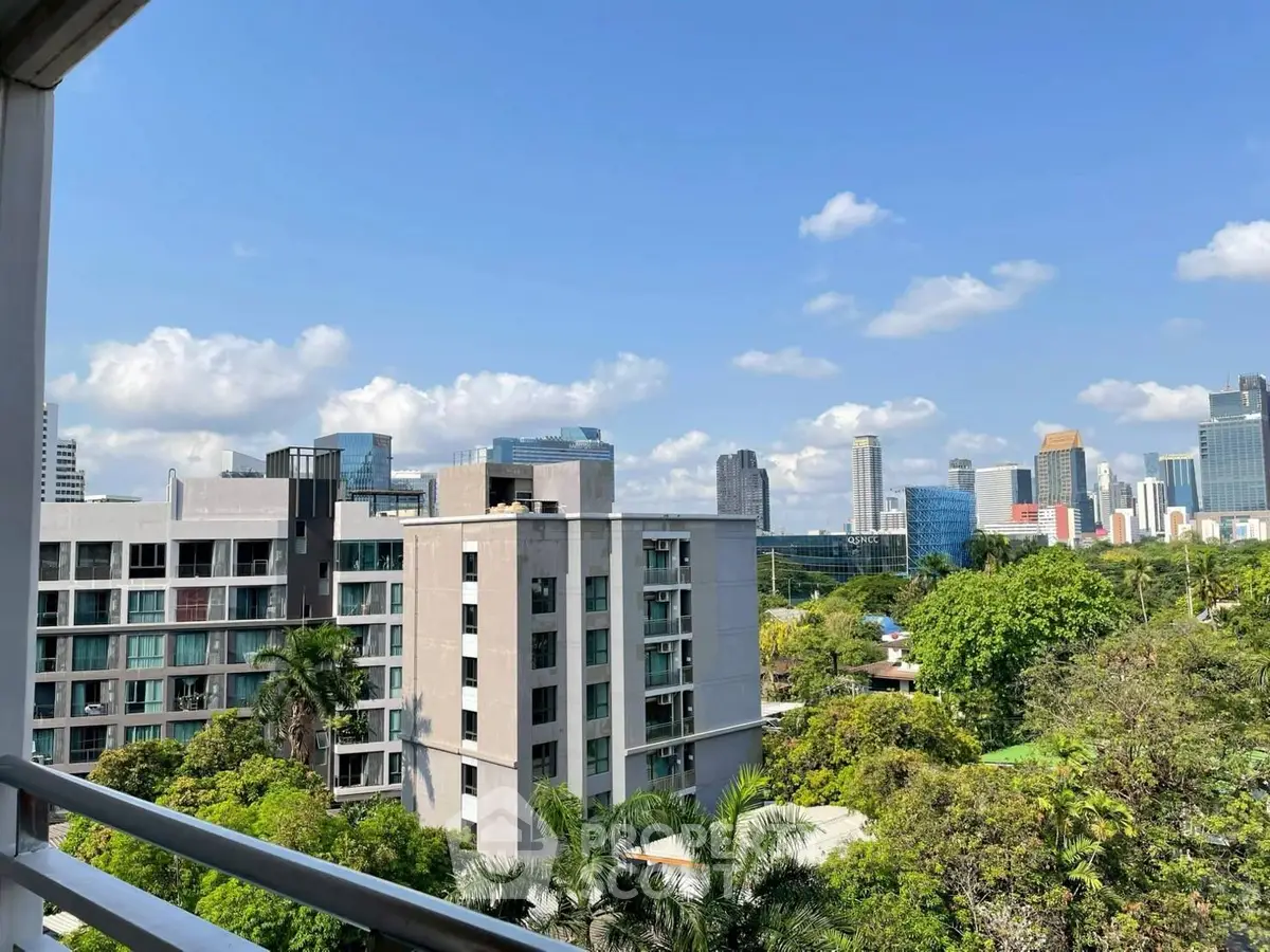 Stunning cityscape view from a high-rise balcony overlooking lush greenery and modern buildings.