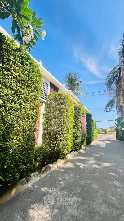 Charming residential building with lush greenery and clear blue sky, perfect for serene living.