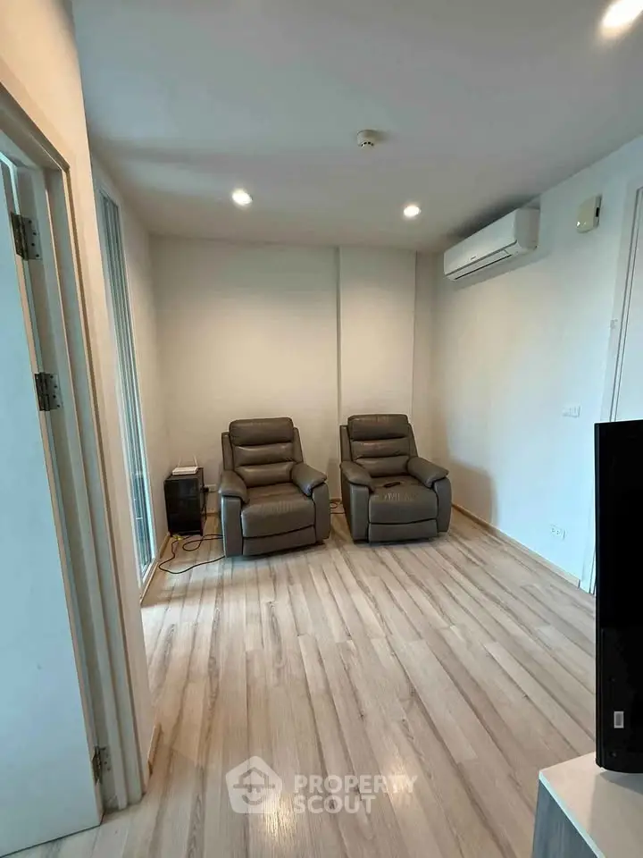 Modern living room with sleek recliners and air conditioning in a cozy apartment.